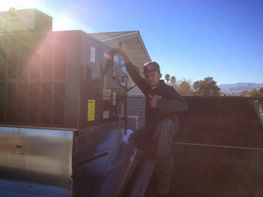 HVAC technician performing Air Duct Cleaning on a rooftop unit in Elbridge