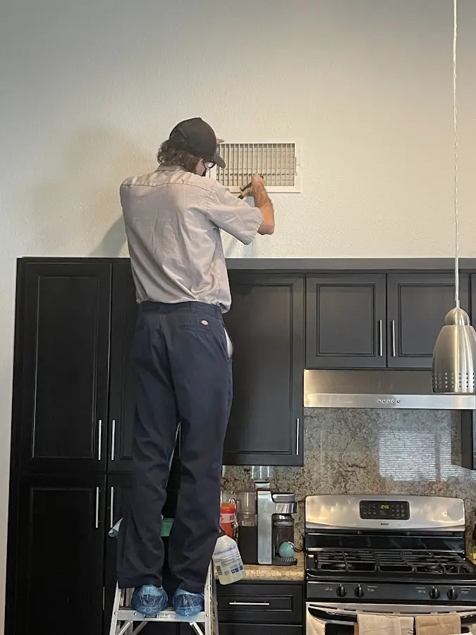 Technician inspecting an air vent during HVAC service in Elbridge